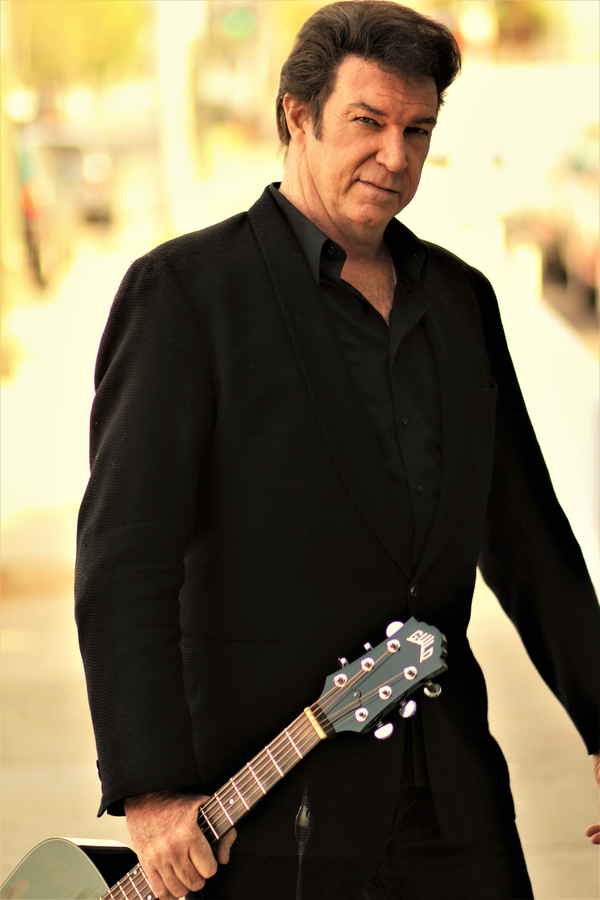 Promotional picture of our Johnny Cash tribute artist wearing all black outfit while posing to camera with guitar | Altus Entertainment